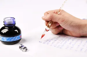 Detailed view of an elegant handmade glass dip pen used for calligraphy with blue ink