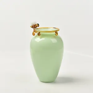 Decorative mint green glass vase featuring a honey bee figurine and amber honey drips