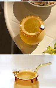Vista detallada de un vaso de cristal ámbar con diseño de abeja y pajita de vidrio
