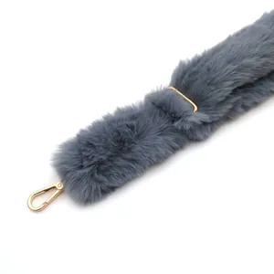 Detalle de correa de bolso de pelo gris con herrajes metalicos dorados, ajustable.