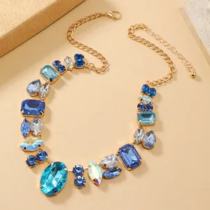 Nahaufnahme einer eleganten Statement-Halskette in Gold mit blauen Kristallen und Zirkonia.