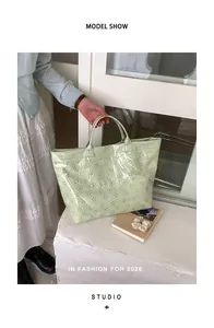 Gros plan d'un sac cabas en PVC vert menthe découpé au laser avec motif floral