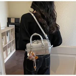 Modern silver metallic bowling handbag worn as a crossbody bag for minimalist fashion style