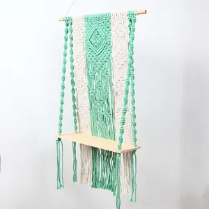 Detailed view of the handmade boho macrame wall hanging shelf with green and beige woven cotton.