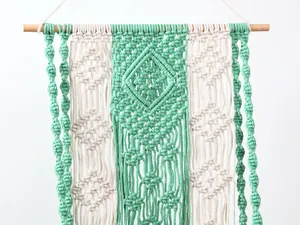 Detailed view of handmade boho macrame wall hanging, mint green and beige cotton decor.