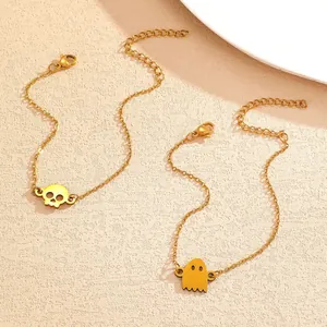 Close-up detail of gold Halloween punk style bracelets with skull and ghost charms on a beige background