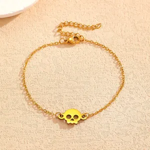 Detailed close-up of a gold-plated punk skull pendant bracelet on textured surface
