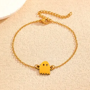 Close-up of a gold ghost pendant bracelet for Halloween on a textured stone surface.