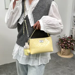 Yellow quilted shoulder bag with metal chain strap and cute bear charm for daily commute.