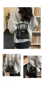 Detailansicht einer stilvollen grauen Beuteltasche mit Plüschbärenanhänger, getragen von einem Model.