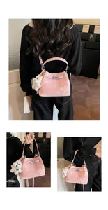 Detailansicht der rosa texturierten Beuteltasche mit weißem Plüsch-Teddybär-Anhänger.