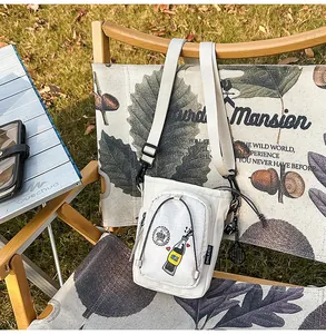 Bolso cruzado casual de lona blanca para exteriores con grafico moderno ideal para viajes.