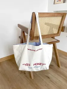 White canvas tote bag with striped lining and red embroidered text for women daily use.