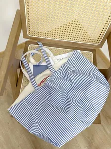 Detail of large striped canvas tote bag, casual shoulder commuting bag for daily student use.