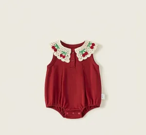 Vue détaillée de la barboteuse bébé rouge avec charmant col brodé de cerises dentelle.