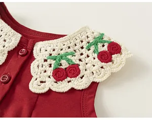 Vue détaillée d'une robe d'été rouge pour bébé fille avec col dentelle crochet et cerises.