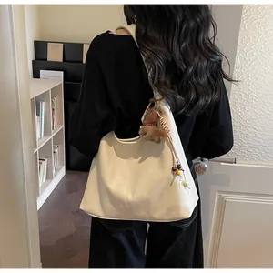 Détail d'un grand sac cabas en cuir souple crème porté par un mannequin à l'intérieur