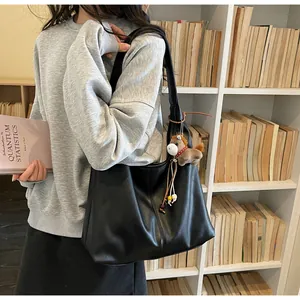 Vue détaillée d'un sac hobo en cuir noir avec charm de cheval en peluche en bibliothèque.