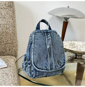 Detailansicht eines blauen Vintage-Jeansrucksacks auf einem modernen Glastisch.