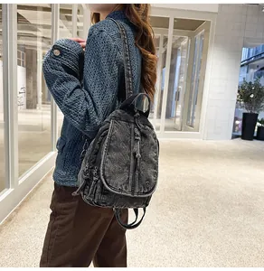 Ein Modell trägt einen Vintage-Rucksack aus gewaschenem Denim in einem modernen Flur.