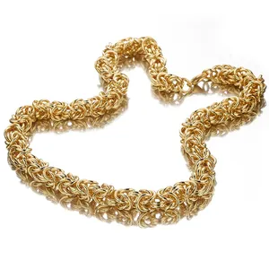 Close-up detail of golden stainless steel Byzantine link chain necklace, glossy metallic texture.