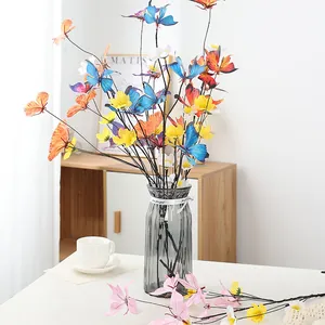 Detailaufnahme des künstlichen Schmetterlingsblumenstraußes in grauer Glasvase für das Haus.