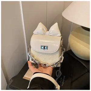 Close-up of cream mini bag with a large bow and silver chain details