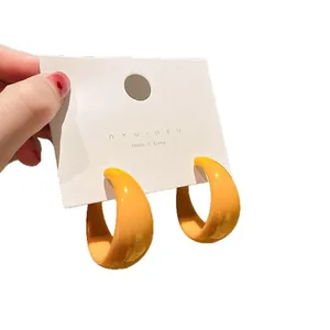 French vintage bright orange resin hoop earrings displayed on white cardboard tag