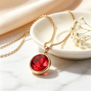 Primer plano de un elegante collar chapado en oro de 18 quilates con colgante rojo.