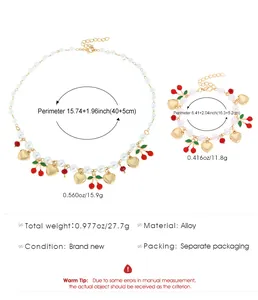 Detailed view of pearl necklace and bracelet set with cherry and gold heart charms