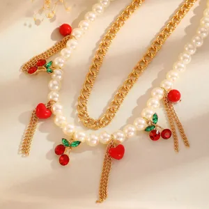 Detailed macro view of a pearl necklace with red crystal cherries and gold chains