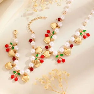 Detailed view of elegant faux pearl necklace with gold hearts and red cherry charms