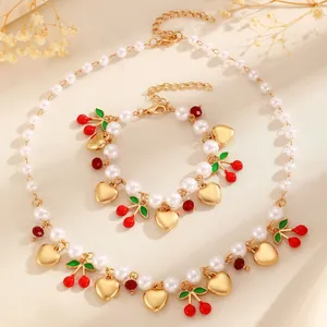 Detailed view of a jewelry set featuring faux pearls, red cherry charms, and golden hearts.