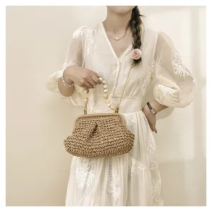 Detail view of straw woven handbag featuring beaded handle, gold chain strap and chic clasp.