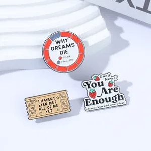 Nahaufnahme von drei inspirierenden Emaille-Pins mit süßen Erdbeeren und Ticket-Designs