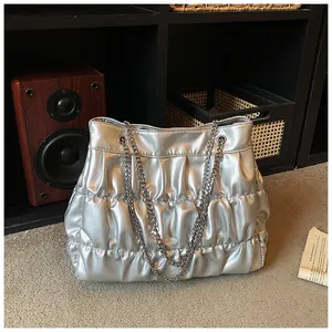 Silver pleated chain tote bag in a casual lifestyle setting showing metallic texture.