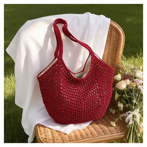 Schicke rote Strick-Häkel-Tasche im gemütlichen Garten-Setting mit Blumen und Korbstuhl-Detail.