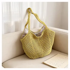Detailaufnahme einer schicken gelben Häkel-Strick-Schultertasche auf einem gemütlichen Sofa.