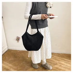 Nahaufnahme der schwarzen gestrickten, durchbrochenen Umhängetasche in gemütlicher Szene.