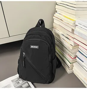 Sac à dos décontracté en nylon noir avec poche zippée avant et livres en arrière-plan pour usage.