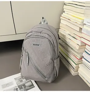 Sac à dos en nylon gris avec poche zippée diagonale élégante, idéal pour le quotidien.
