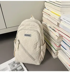 Sac à dos minimaliste en nylon beige, doté d'une poche avant pratique et d'une fermeture éclair.