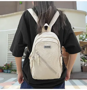 Gros plan du sac à dos décontracté en nylon beige avec une poche avant zippée pratique.