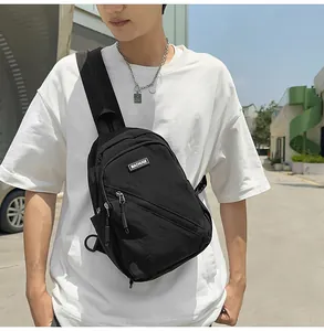 Gros plan détail du sac de poitrine en nylon noir, présentant des poches zippées et style.