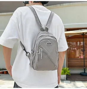 Vue détaillée du sac à dos multifonction en nylon gris avec fermeture éclair et étiquette.