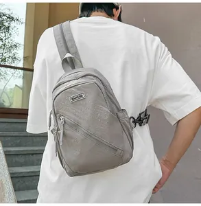 Vue détaillée du sac bandoulière nylon gris porté par le modèle, montrant sangle et fermeture.