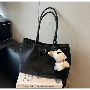 Detalle de cerca del bolso tote retro negro con un lindo amuleto de perro de peluche