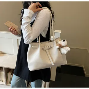 Primer plano del elegante bolso tote beige con bonito colgante de cachorro y cinturón.