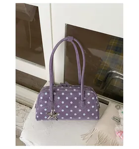 Detailed close-up shot of purple polka dot handbag with star charm on clean white surface.