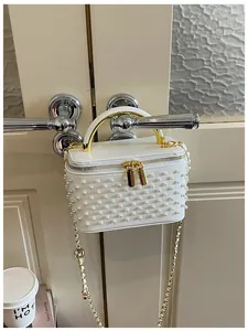 White pearl box shoulder bag detail view, chic mini handbag with gold chain straps.